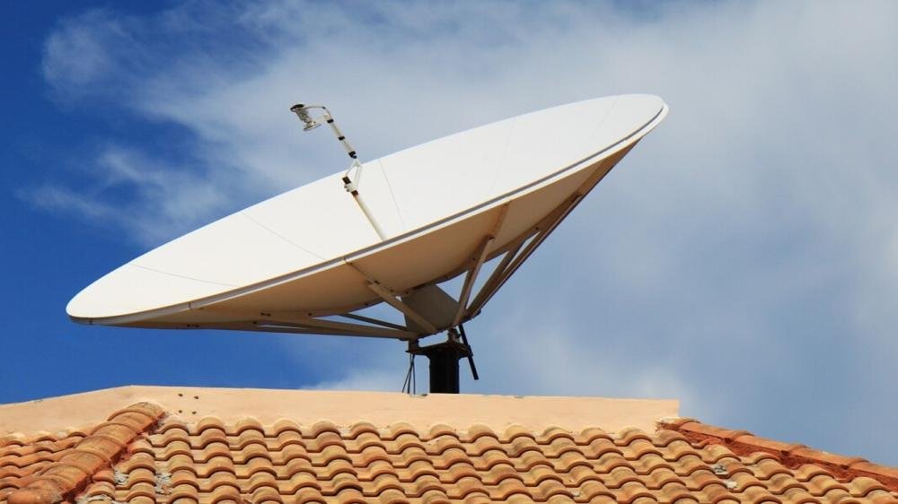 Antena digital, sobre um telhado, em um dia de céu aberto