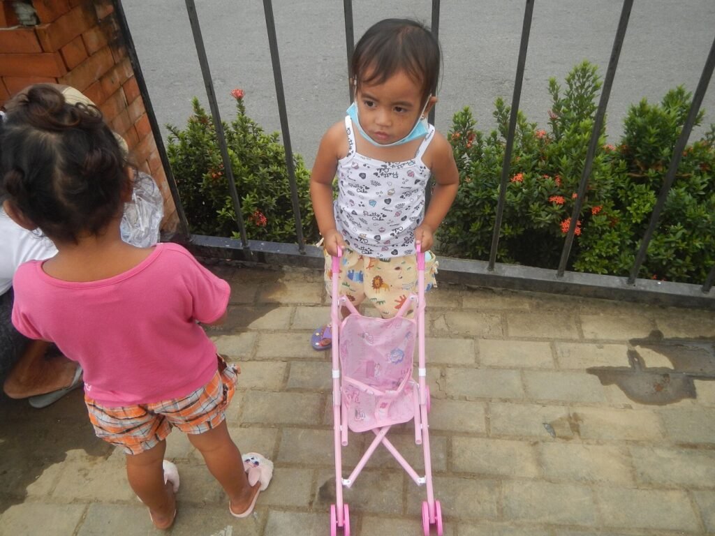 Young girls with toy baby carriage