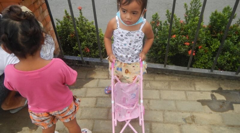 Young girls with toy baby carriage