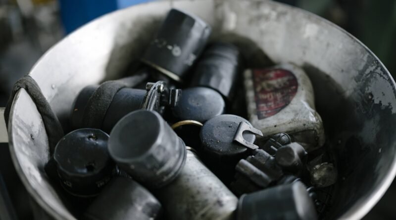 A metal bowl holds various automotive tools and parts in an automotive workshop. This scene shows the collected items needed for different repairs and