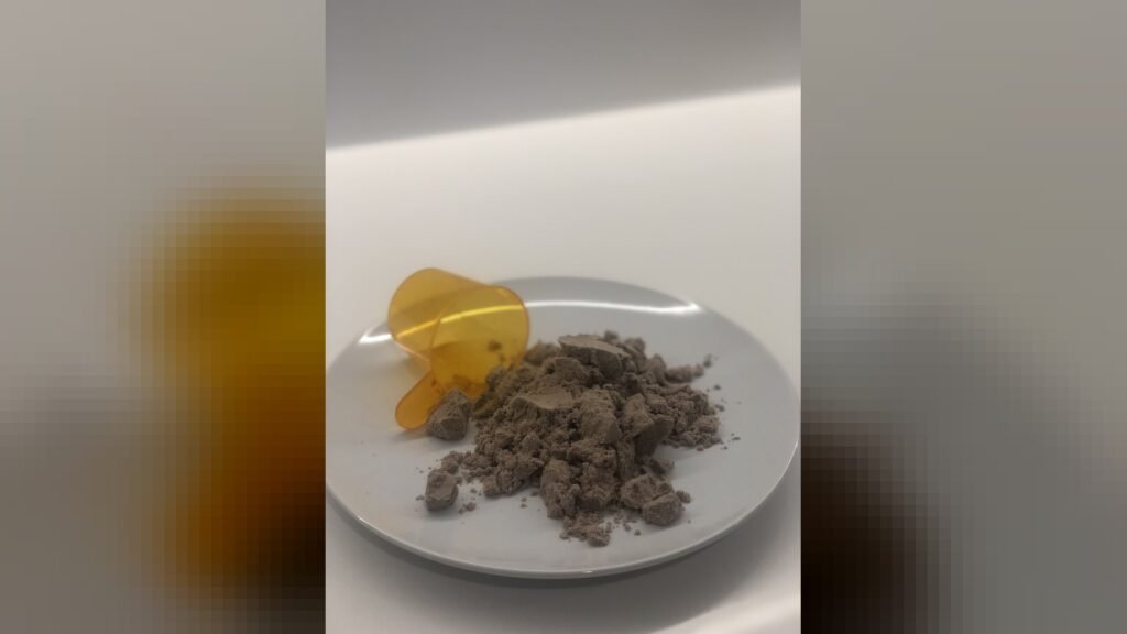 Chocolate flavoured pea protein powder pictured with its serving scoop.