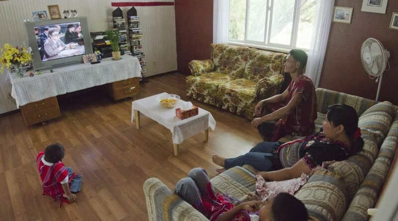 Saw "Richard" Peter, Naw Susu, and their sons watch television in the living room of the first home that own in the United States, in Delta, Colorado,